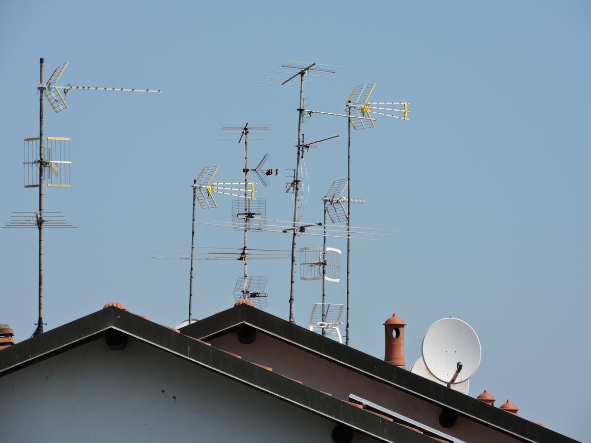 Television antennas on a rooftop against a blue sky