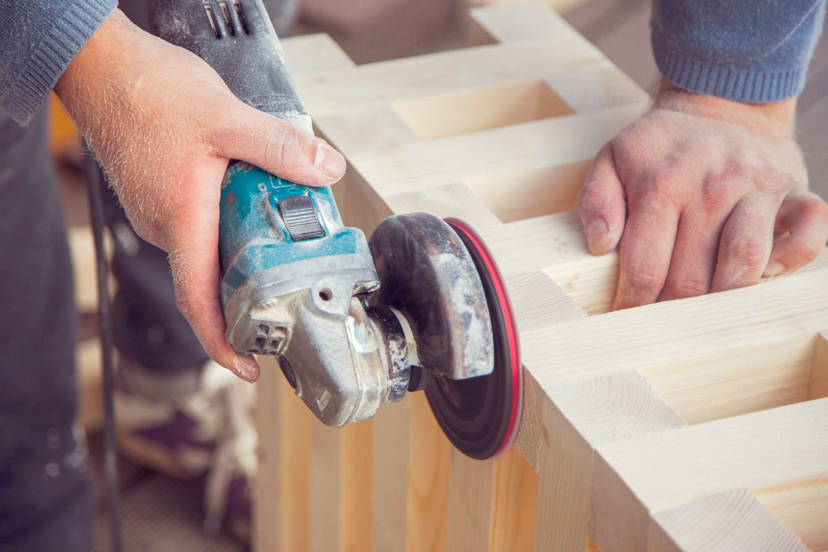Carpenter polishing wood with an angle grinder