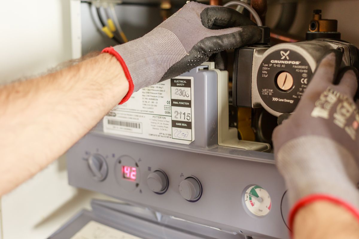 Hands adjusting a boiler and heating system